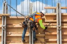 un obrero de la construcción martilla un clavo en una casa que está construyendo